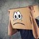 Man with cardboard box on his head and sad crying face expression. Concept of sadness and depression.