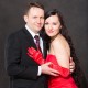 Portrait of happy couple in love posing at studio on gray background dressed in red. Attractive man and woman.